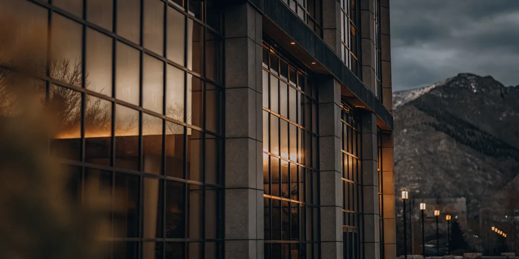 Modern commercial building exterior with glass facade and mountain backdrop at golden hour